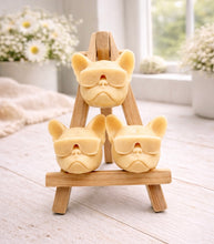 Load image into Gallery viewer, A set of three handmade vegan soaps in the shape of French Bulldog heads wearing sunglasses, displayed on a wooden easel in a bright, modern bathroom setting.
