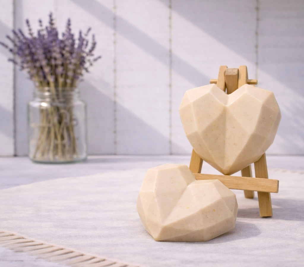 Two geometric heart-shaped vegan soaps on a stand with a jar of lavender in the background.