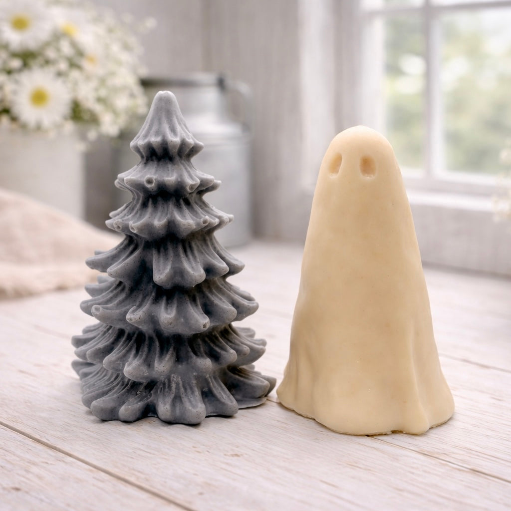 handmade ghost soap standing next to a grey textured Christmas tree sculpture soap, displayed on a rustic white wooden surface in a bright farmhouse decor setting.