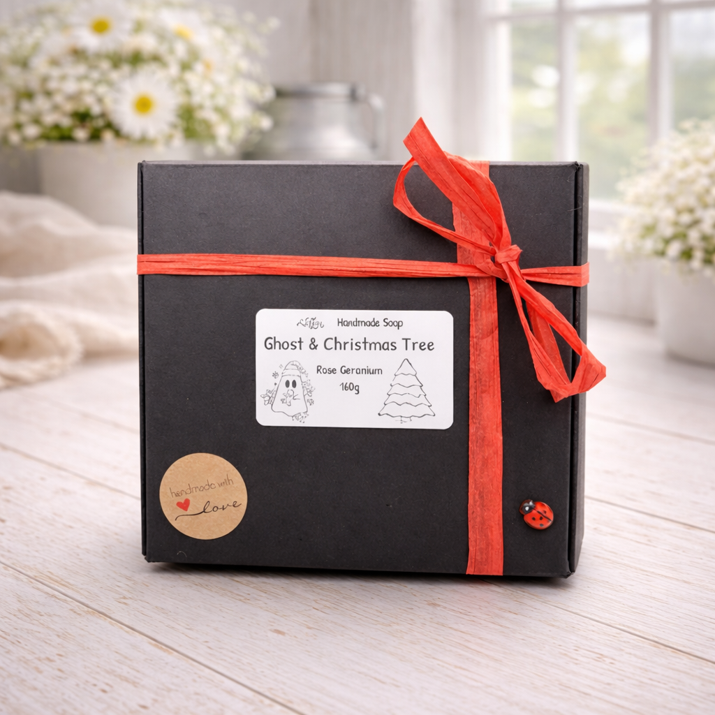 Black gift box with red ribbon and 'Ghost & Christmas Tree' label on a light wooden surface.