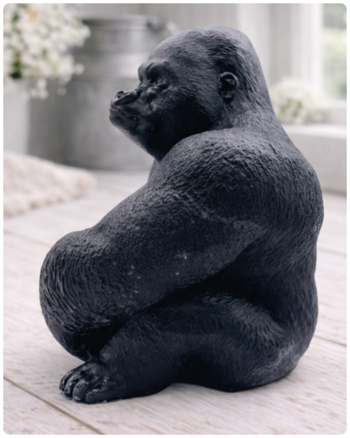A large highly detailed handmade vegan soap in the shape of a sitting gorilla with realistic fur and muscle textures, displayed on a light wooden surface.
