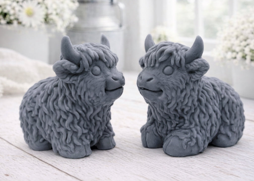 A highly detailed handmade vegan soap sculpted in the shape of a highland cow with long, flowing fur texture, a sweet face with a large snout, and prominent horns, displayed on a light wooden surface in a bright farmhouse setting.