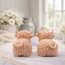Load image into Gallery viewer, A highly detailed handmade vegan soap sculpted in the shape of a highland cow with long, flowing fur texture, a sweet face with a large snout, and prominent horns, displayed on a light wooden surface in a bright farmhouse setting.
