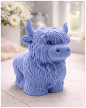 Load image into Gallery viewer, A detailed handmade vegan soap in a sculpted in the shape of a highland cow with characteristic long, wavy fur, horns, and a friendly face, displayed on a light wooden surface
