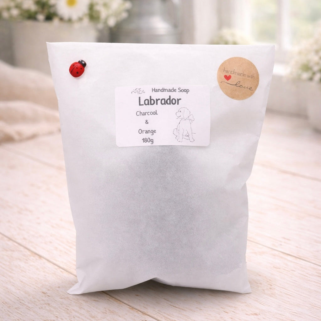White soap bag labeled 'Labrador' with a small red ladybug on a light wooden surface.
