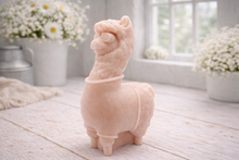 Load image into Gallery viewer, handmade vegan soap in the shape of a realistic standing alpaca or llama sculpture, featuring a smooth body with detailed fur texture on the head and neck, displayed in a bright farmhouse decor setting.
