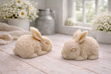 Load image into Gallery viewer, handmade vegan soaps in the shape of realistic crouching rabbits with detailed fur texture, displayed on a rustic white wooden surface in a bright farmhouse decor setting.
