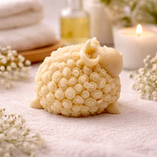 Load image into Gallery viewer, handmade vegan soap in the shape of a realistic smiling ram with curved horns and detailed curly wool texture, displayed on a rustic wooden surface with lavender and white flowers.
