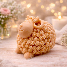 Load image into Gallery viewer, handmade vegan soap in the shape of a realistic smiling ram with curved horns and detailed curly wool texture, displayed on a rustic wooden surface with lavender and white flowers.
