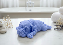Load image into Gallery viewer, A highly detailed handmade vegan soap in a sophisticated slate-grey tone, sculpted in the shape of a Shar Pei puppy lying flat on its stomach with its head resting on its paws, featuring realistic deep skin folds and wrinkles.
