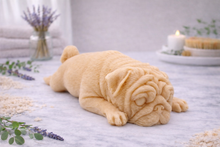 Load image into Gallery viewer, handmade vegan soap in the shape of a realistic sleeping pug dog lying flat, showing detailed wrinkles and fur texture, displayed in a spa-like setting with a candle and lavender.
