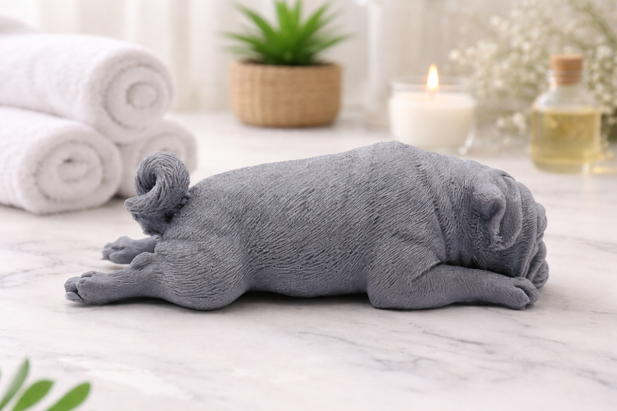 handmade vegan soap in the shape of a realistic sleeping pug dog lying flat, showing detailed wrinkles and fur texture, displayed in a spa-like setting with a candle and lavender.