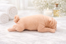Load image into Gallery viewer, handmade vegan soap in the shape of a realistic sleeping pug dog lying flat, showing detailed wrinkles and fur texture, displayed in a spa-like setting with a candle and lavender.
