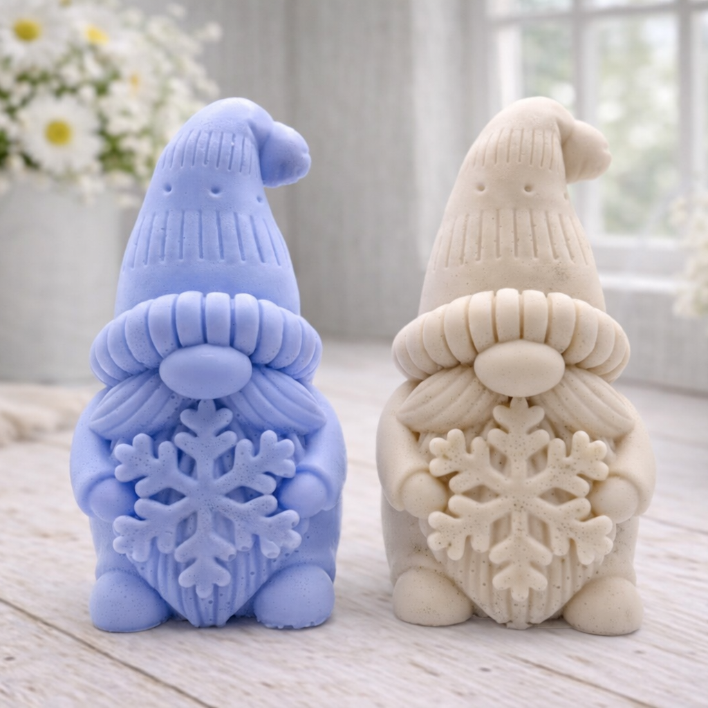 handmade vegan soap in the shape of a winter gnome sculpture holding a large snowflake, featuring a tall textured hat and a bushy moustache , displayed on a rustic white wooden surface with daisies and a milk churn in the background.