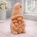 handmade vegan soap in the shape of a winter gnome sculpture holding a large snowflake, featuring a tall textured hat and a bushy moustache , displayed on a rustic white wooden surface with daisies and a milk churn in the background.