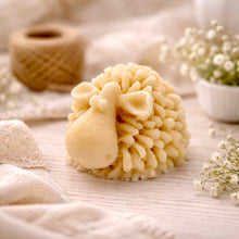 Load image into Gallery viewer, A set of three handmade vegan soaps in different sheep styles, including a dark grey smiling sheep and two lambs with detailed woolly textures, displayed on a rustic wooden surface with lavender and flowers.
