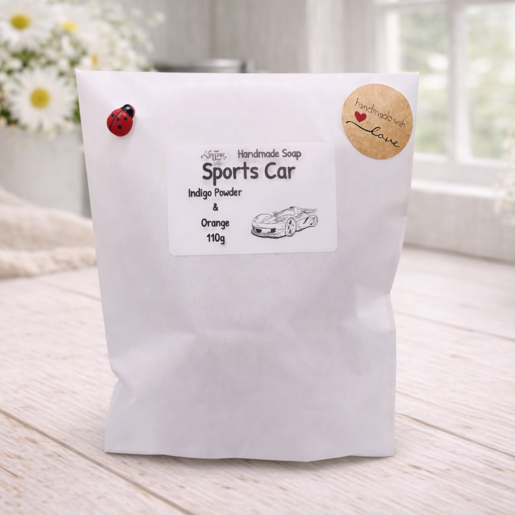 handmade vegan soap in the shape of a sleek supercar sculpture, featuring aerodynamic curves and detailed wheels, displayed on a rustic white wooden surface in a bright farmhouse decor setting.