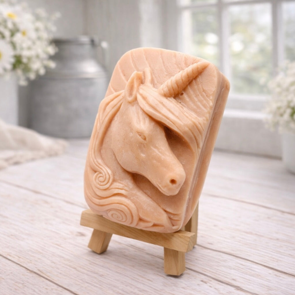 handmade vegan soap featuring a detailed unicorn head relief with a spiralled horn and flowing curly mane, displayed on a small wooden easel in a bright farmhouse decor setting.