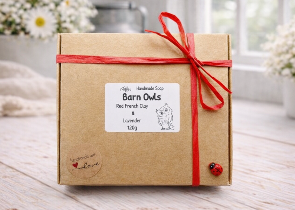Gift box with a red ribbon on a wooden surface with flowers in the background