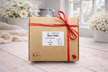 Load image into Gallery viewer, Gift box with a red ribbon on a wooden surface with flowers in the background
