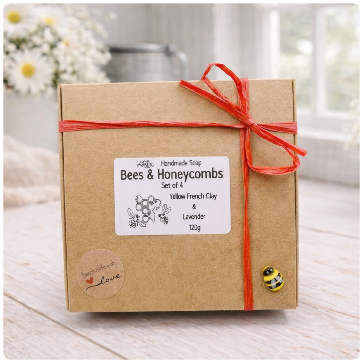 A handmade vegan soap gift set featuring six hexagonal bars stacked in a pyramid on a small wooden easel; some bars show a honeybee relief and others a honeycomb pattern