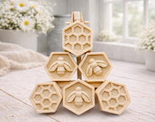 Load image into Gallery viewer, A handmade vegan soap gift set featuring six hexagonal bars stacked in a pyramid on a small wooden easel; some bars show a honeybee relief and others a honeycomb pattern
