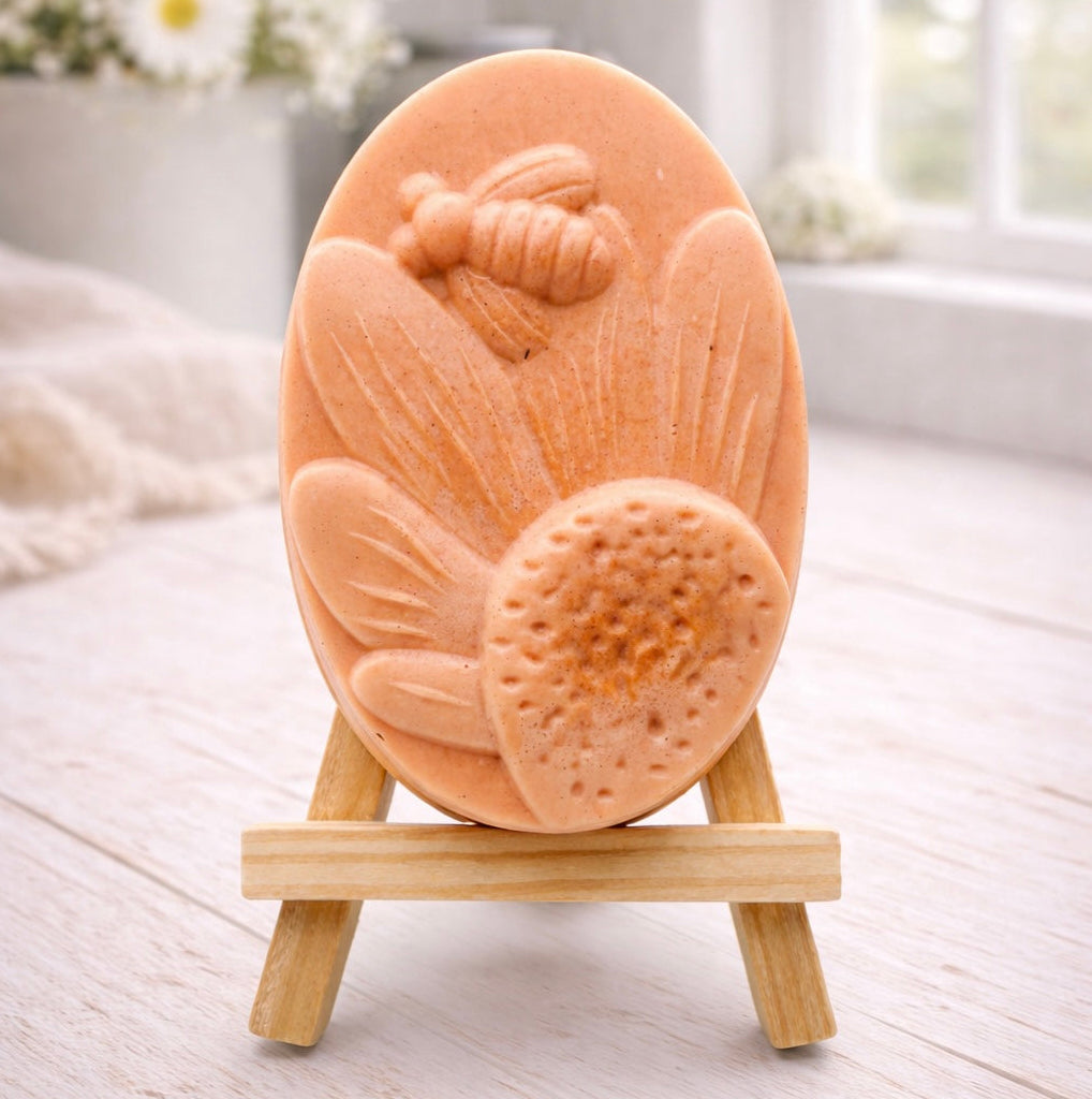 handmade vegan soap gift featuring a detailed honey bee landing on a large sunflower, displayed on a wooden easel against a whimsical farmhouse decor background.