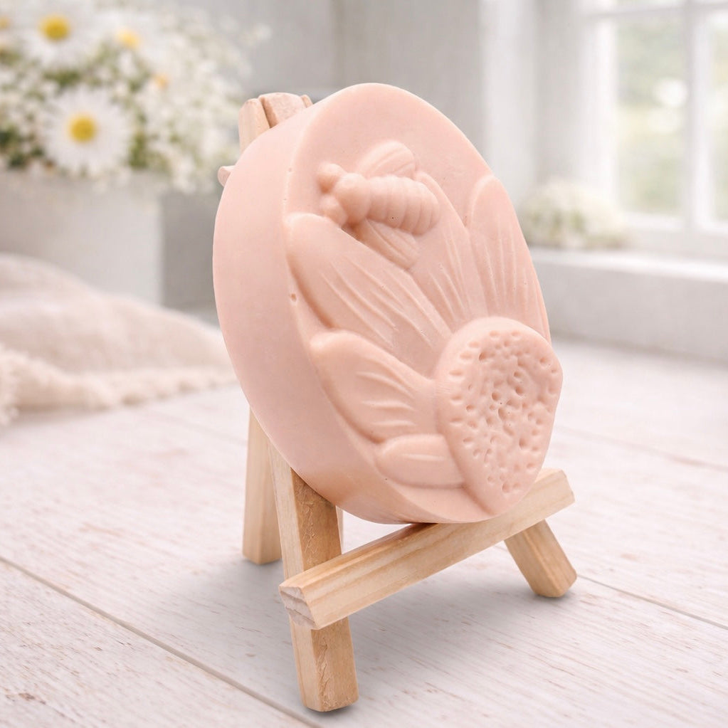 handmade vegan soap gift featuring a detailed honey bee landing on a large sunflower, displayed on a wooden easel against a whimsical farmhouse decor background.