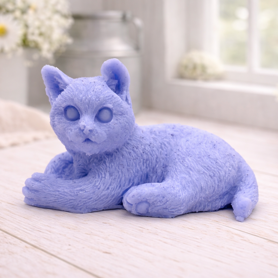 A highly detailed handmade vegan soap sculpted in the shape of a sitting cat with its tail curled around its paws, featuring realistic fur texture and a sweet facial expression, displayed on a light wooden surface.