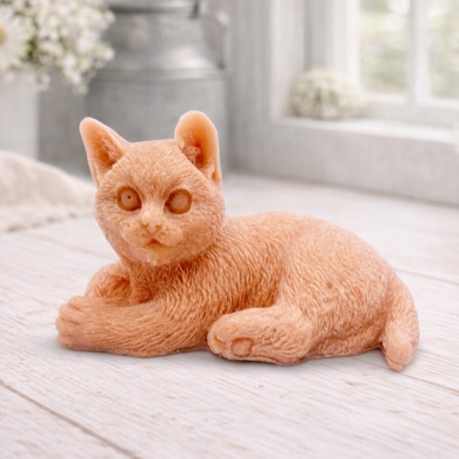 A highly detailed handmade vegan soap sculpted in the shape of a sitting cat with its tail curled around its paws, featuring realistic fur texture and a sweet facial expression, displayed on a light wooden surface.