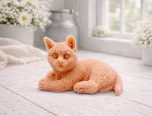 Load image into Gallery viewer, A highly detailed handmade vegan soap sculpted in the shape of a sitting cat with its tail curled around its paws, featuring realistic fur texture and a sweet facial expression, displayed on a light wooden surface.
