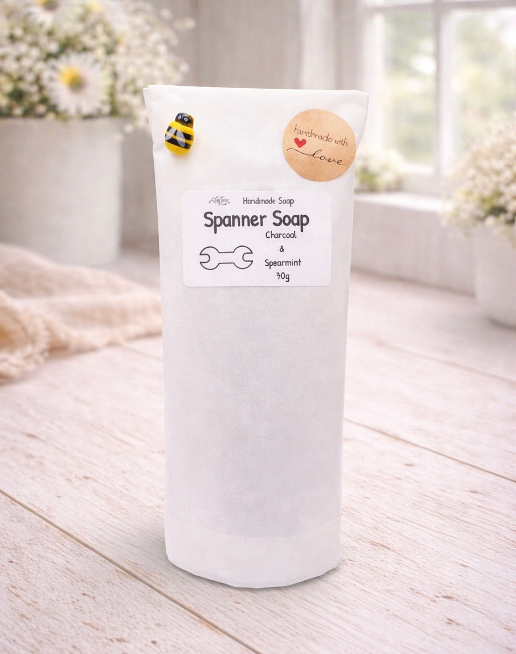 Spanner Soap packaging on a wooden surface with a blurred floral background
