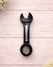 Load image into Gallery viewer, A 3D handmade vegan soap sculpted in the shape of a realistic spanner or wrench tool, finished in a sleek charcoal black with silver-painted detailing on the handle and head, lying on a light wood surface.
