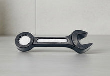 Load image into Gallery viewer, A 3D handmade vegan soap sculpted in the shape of a realistic spanner or wrench tool, finished in a sleek charcoal black with silver-painted detailing on the handle and head, lying on a light wood surface.
