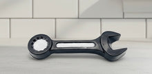 Load image into Gallery viewer, A 3D handmade vegan soap sculpted in the shape of a realistic spanner or wrench tool, finished in a sleek charcoal black with silver-painted detailing on the handle and head, lying on a light wood surface.
