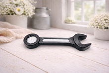 Load image into Gallery viewer, A 3D handmade vegan soap sculpted in the shape of a realistic spanner or wrench tool, finished in a sleek charcoal black with silver-painted detailing on the handle and head, lying on a light wood surface.
