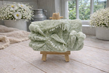 Load image into Gallery viewer, A rectangular handmade vegan soap  featuring a high-relief carving of a Tyrannosaurus Rex with its jaws wide open in a roar and sharp claws framing the face, displayed on a miniature wooden easel.
