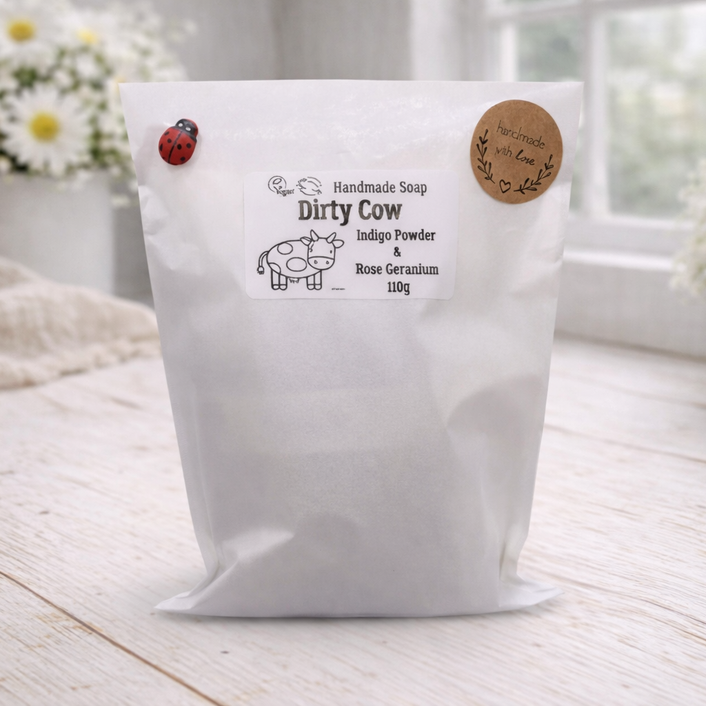 White bag labeled 'Dirty Cow' on a wooden surface with flowers in the background