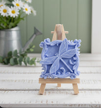 Load image into Gallery viewer, A beautiful handmade vegan soap in a natural tone, featuring a highly detailed relief of a dragonfly with delicate, outspread wings and a textured body, displayed on a miniature wooden easel against a soft farmhouse background.
