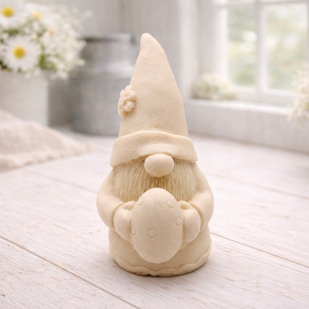 A detailed handmade vegan soap gift,  sculpted as a whimsical Easter gnome (gonk) wearing a tall pointed hat with a flower detail, holding a large patterned Easter egg.