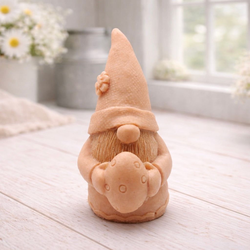 A detailed handmade vegan soap gift,  sculpted as a whimsical Easter gnome (gonk) wearing a tall pointed hat with a flower detail, holding a large patterned Easter egg.
