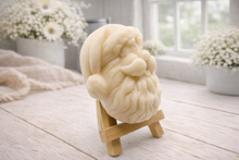Load image into Gallery viewer, handmade vegan soap sculpted in the shape of Father Christmas's head, featuring a detailed curly beard, a jolly moustache, and a classic Santa hat, displayed on a miniature wooden easel in a bright farmhouse setting.
