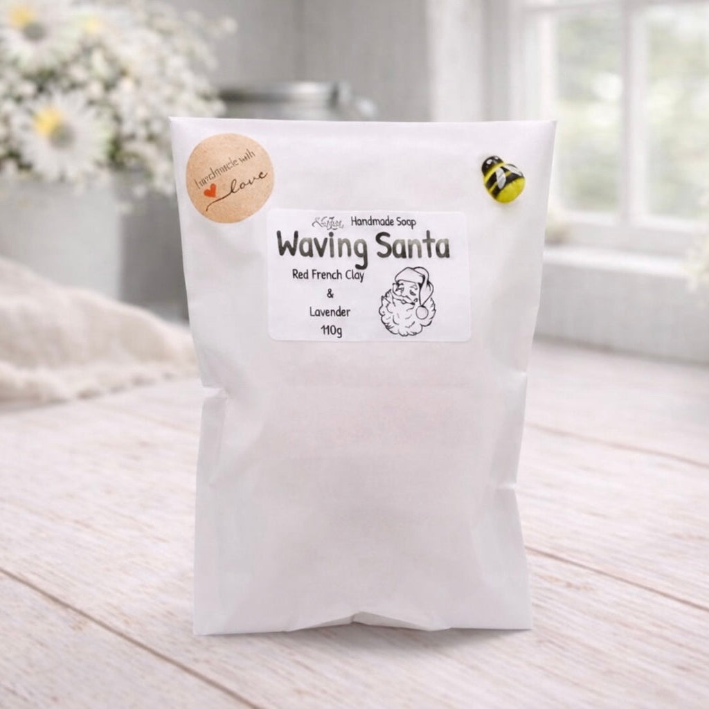 White bag labeled 'Waving Santa' on a light wooden surface with flowers in the background