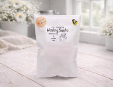 Load image into Gallery viewer, White bag labeled 'Waving Santa' on a light wooden surface with flowers in the background
