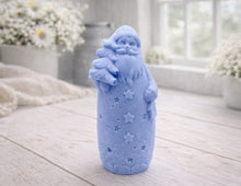 Load image into Gallery viewer, handmade vegan soap sculpted into a tall figure of Father Christmas wearing star-patterned robes, holding a small Christmas tree in one arm and a lantern in the other, set in a bright farmhouse window.
