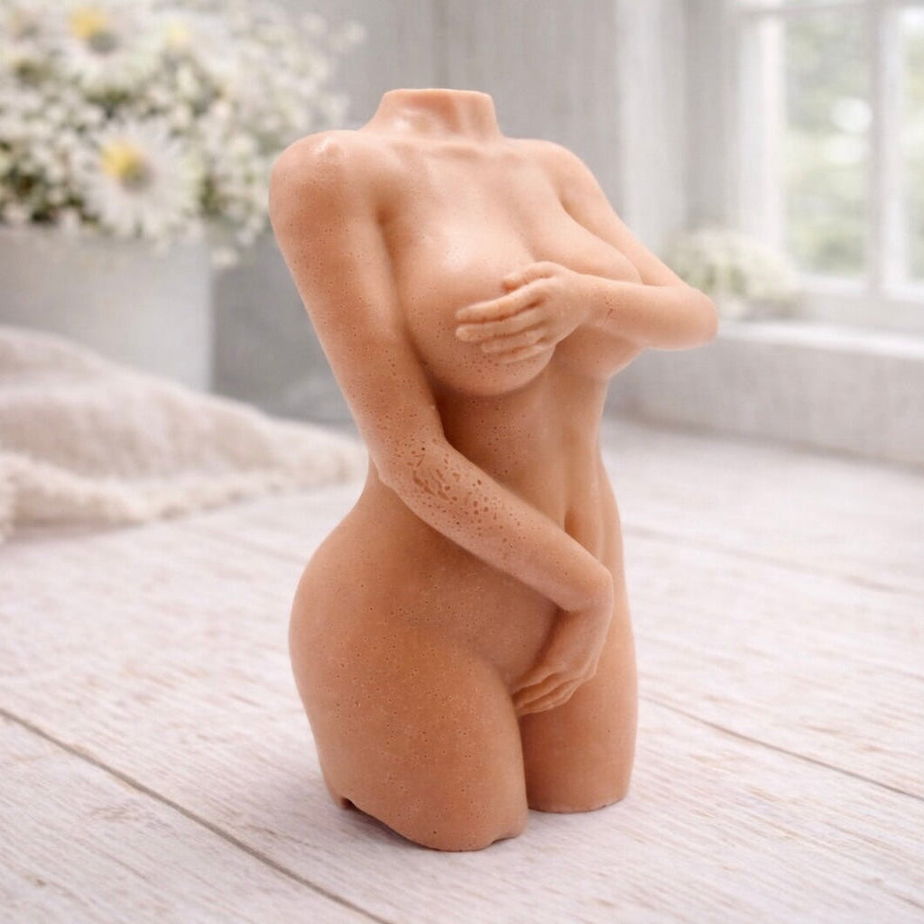 A handmade vegan soap sculpted into a detailed female torso with soft, realistic curves and defined musculature and displayed in a bright farmhouse setting.