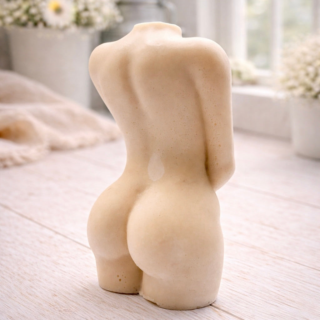 A 3D handmade vegan soap sculpted into a detailed female torso with soft, realistic curves and defined musculature and displayed in a bright farmhouse setting.