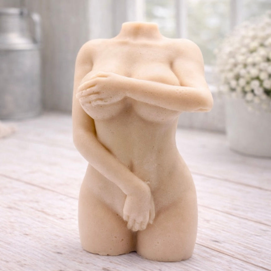 A 3D handmade vegan soap sculpted into a detailed female torso with soft, realistic curves and defined musculature and displayed in a bright farmhouse setting.