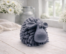 Load image into Gallery viewer, A highly detailed handmade vegan soap sculpted in the shape of a fluffy sheep with thick, textured wool and a smooth face, displayed on a light wooden surface in a farmhouse-style setting.
