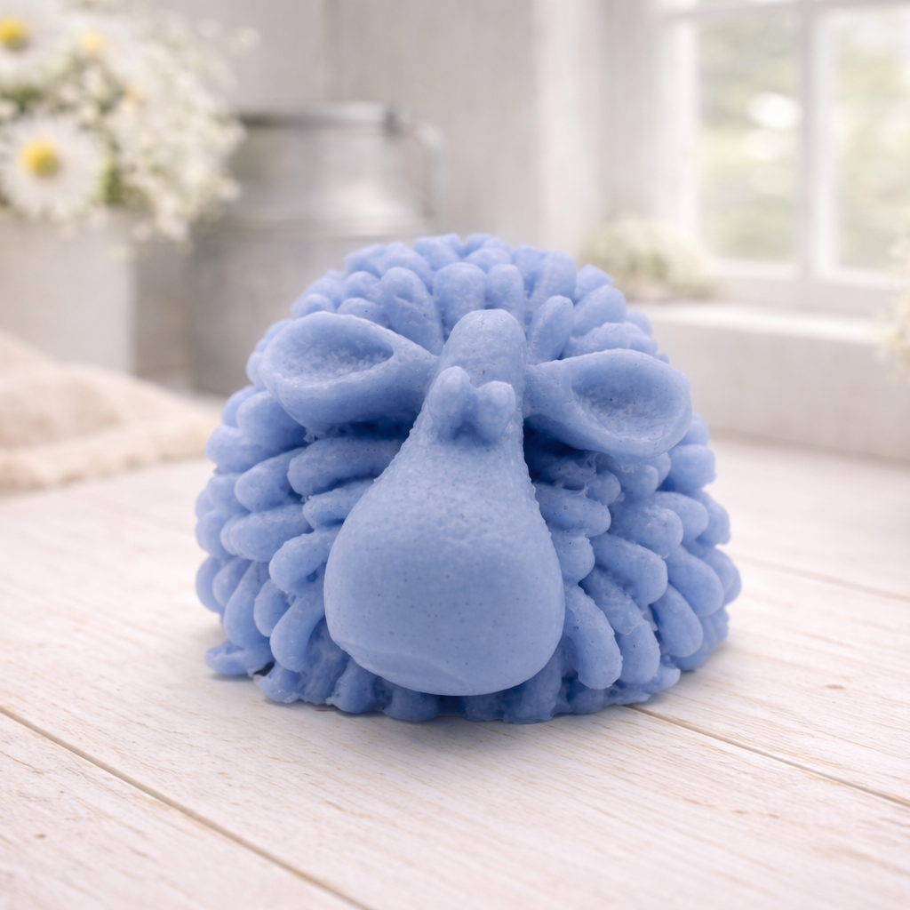 A highly detailed handmade vegan soap sculpted in the shape of a fluffy sheep with thick, textured wool and a smooth face, displayed on a light wooden surface in a farmhouse-style setting.